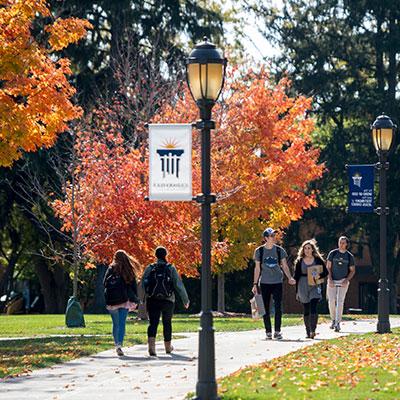 Students walk down a sidewalk in the fall